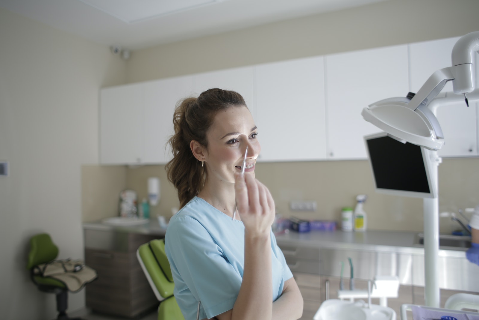 Smiling female dentist in uniform standing with dental tweezers