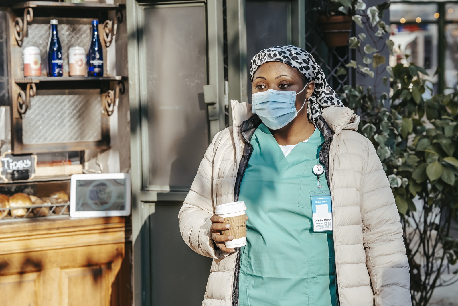 A traveling nurse in mask drinking coffee in street